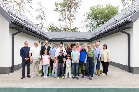 Група людей різного віку стоїть перед новою будівлею