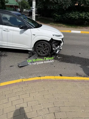 Білий автомобіль з пошкодженою передньою частиною на дорозі