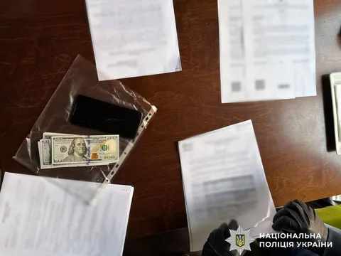 Долари США та документи на столі під час розслідування