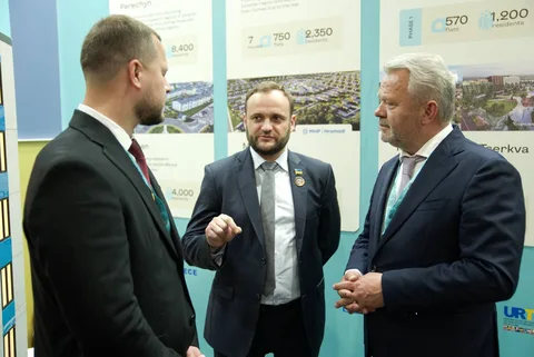 Три чоловіки в костюмах обговорюють проект біля стенду