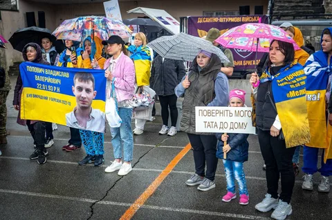 Люди з українськими прапорами на мітингу під дощем