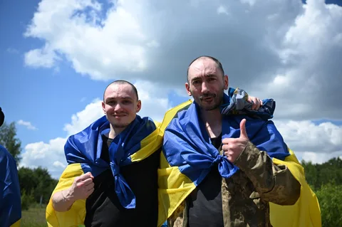 Двоє чоловіків у синьо-жовтих курткахпоказують жест перемоги