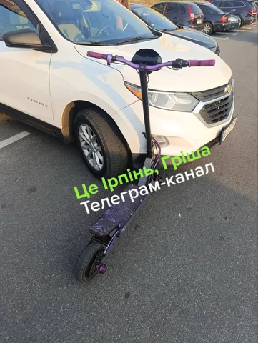 Електричний самокат біля пошкодженого припаркованого автомобіля
