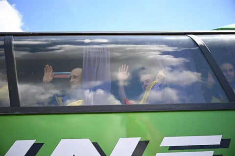 Люди за вікном автобуса махають руками