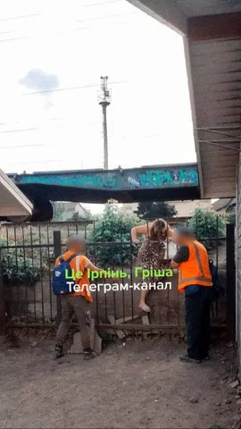 Комунальники в помаранчевих жилетах заварюють паркан біля залізничних колій