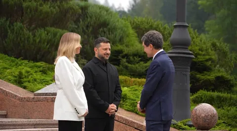 Три люди в діловому одязі спілкуються в парку біля пам'ятника