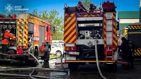Пожежні автомобілі з рукавами біля будівлі