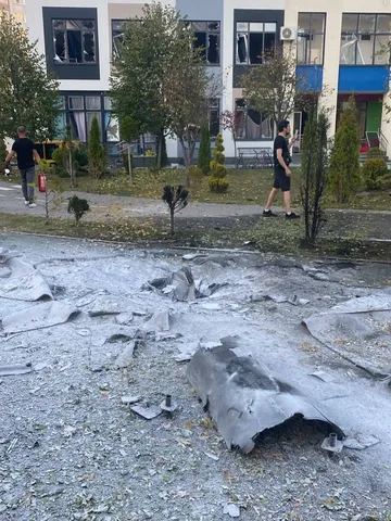 Пошкоджена асфальтова площадка біля будівлі з вирвами та уламками