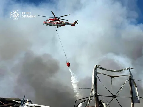 Гелікоптер скидає воду на пожежу зі складу