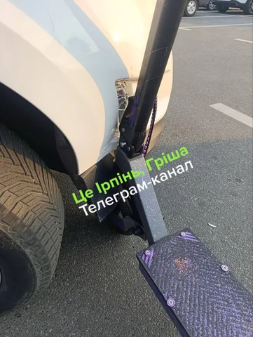 Пошкоджений самокат біля припаркованого автомобіля на парковці