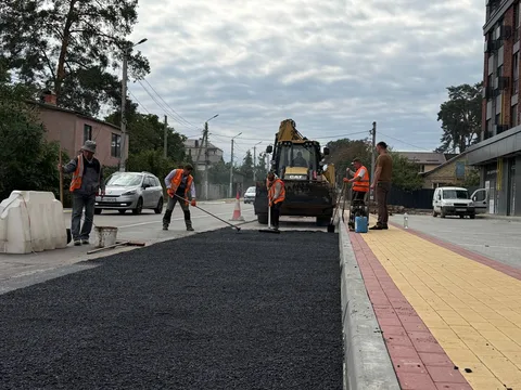Робітники в жилетах укладають асфальт на вулиці Соборній в Ірпені