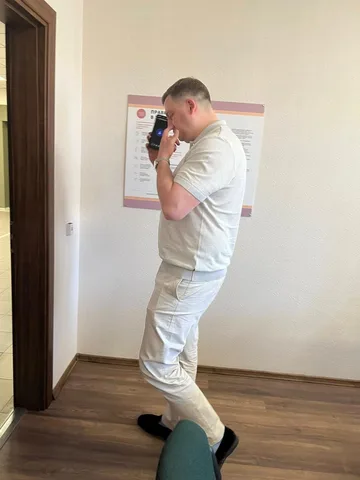 Чоловік у світлому одязі фотографує документ на стіні