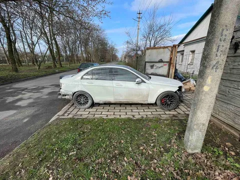 Білий автомобіль припаркований на вулиці біля будинку