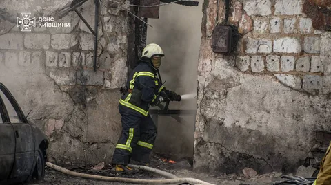 Пожежник гасить пожежу в пошкодженій будівлі складу