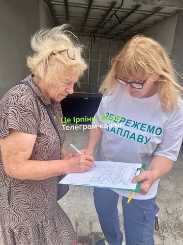 Дві жінки розглядають документ з петицією проти забудови