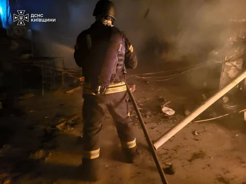 Рятувальник гасить пожежу в пошкодженій будівлі вночі
