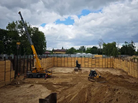 Будівельний майданчик з жовтими огородженнями та технікою