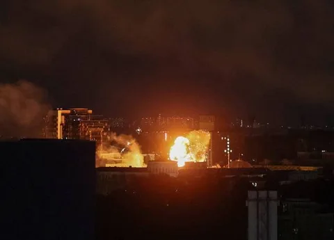 Нічний вид міста з вибухами та вогнем на горизонті