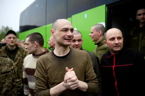 Група чоловіків у військовому одязі біля зеленого автобуса