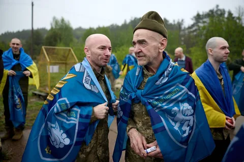 Повернені військові в синіх накидках на території обміну