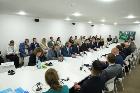 Учасники конференції сидять за довгим столом в залі