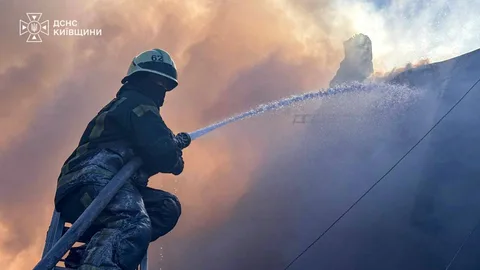 Пожежник гасить пожежу водою з рукава