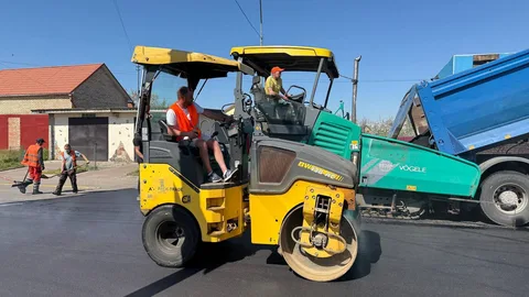 Дорожний каток жовтого кольору на асфальті