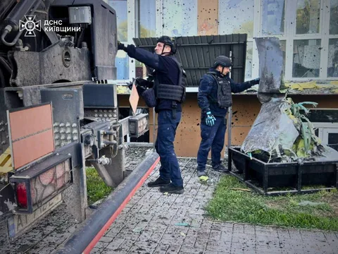Поліцейські оглядають пошкоджену будівлю з вибоїною в стіні