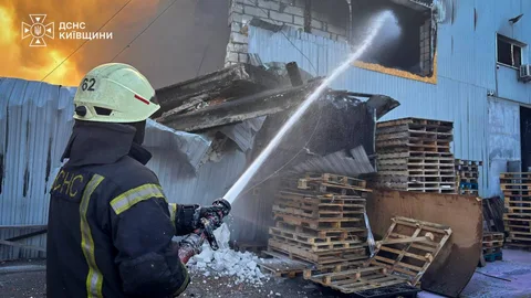 Рятувальник гасить пожежу на складі з деревом