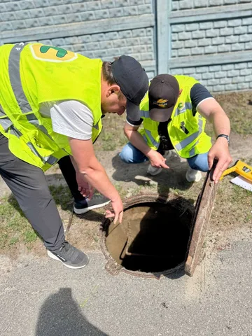 Робітники в жилетах перевіряють люк водопровідної мережі