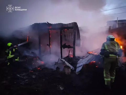 Пожежники гасять палаючу господарську будівлю вночі
