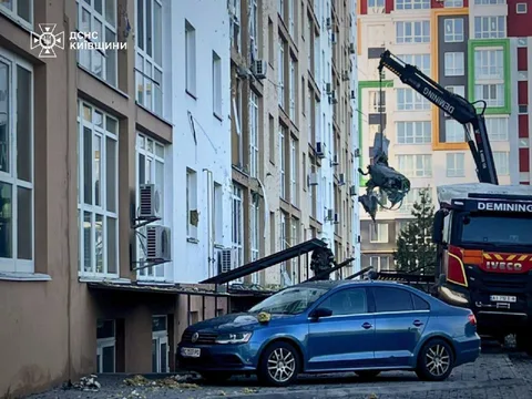 Пошкоджена синя автівка під зруйнованим балконом багатоповерхівки