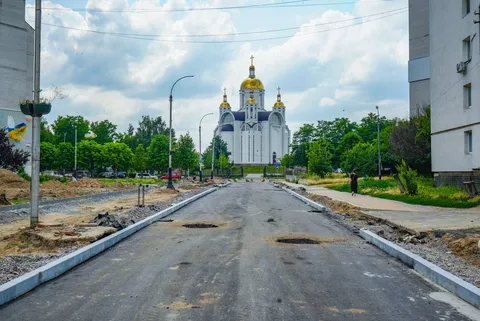 Вулиця з новим асфальтом і церквою з золотими куполами на фоні