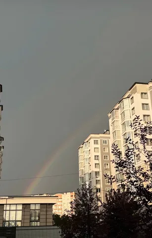 Подвійна веселка над житловими будинками після дощу