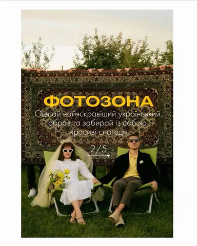 Дві жінки сидять на траві біля декоративного щита