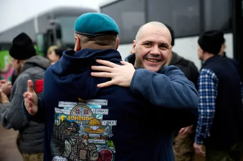 Чоловік обіймає повернутого військового біля автобуса