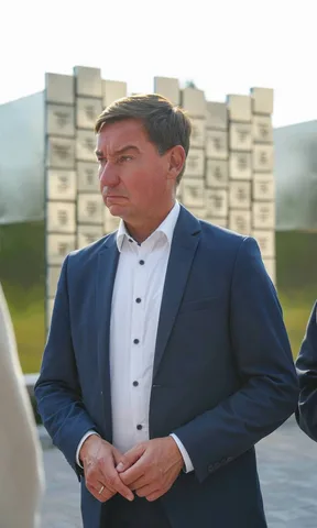 Чоловік у темному костюмі біля будівлі