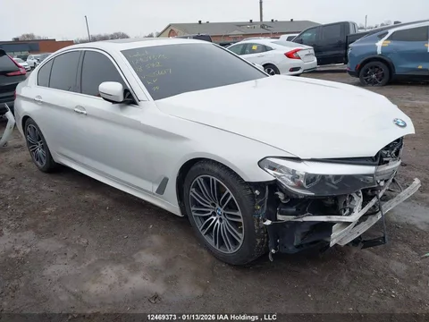 Білий седан BMW з пошкодженою передньою частиною на автостоянці