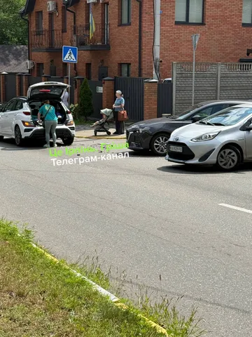 Два автомобілі на дорозі біля цегляного будинку