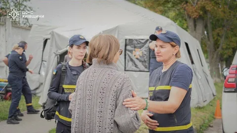 Рятувальники ДСНС спілкуються з жінкою біля намету