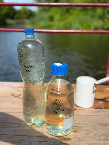 Дві пляшки з водою для аналізу на столі біля річки