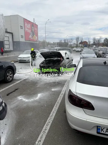 Автомобіль з відкритим капотом на парковці, рядом людина в жилеті