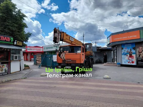 Автокран на площі біля магазинів і реклам