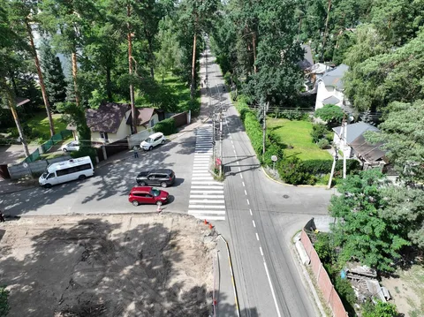 Вид з висоти на перехрестя з круговим рухом, припаркованими автомобілями та зеленню
