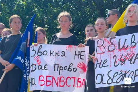 Група людей на мітингу з плакатами українською мовою та прапорами