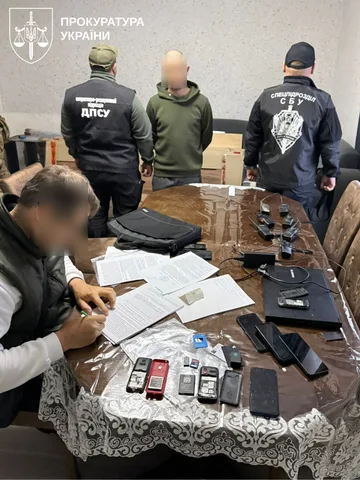 Затримання підозрюваних під час слідчої дії, на столі документи та мобільні телефони
