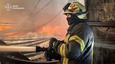 Пожежник з шлангом гасить пожежу на будівлі