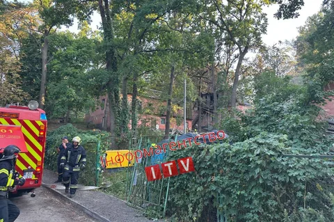 Пожежна машина та рятувальники біля будівлі зі сходами