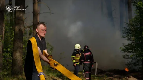 Рятувальник тримає пожежний шланг під час гасіння лісової пожежі
