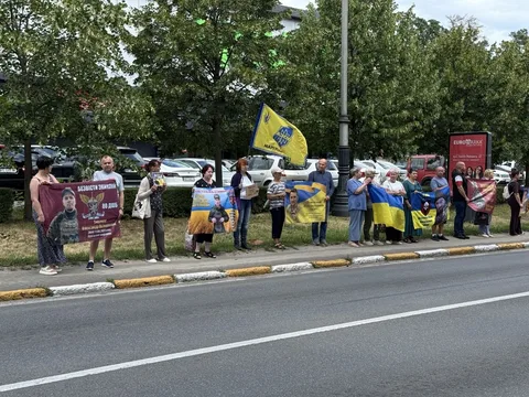 Група людей з плакатами та прапорами на узбіччі дороги